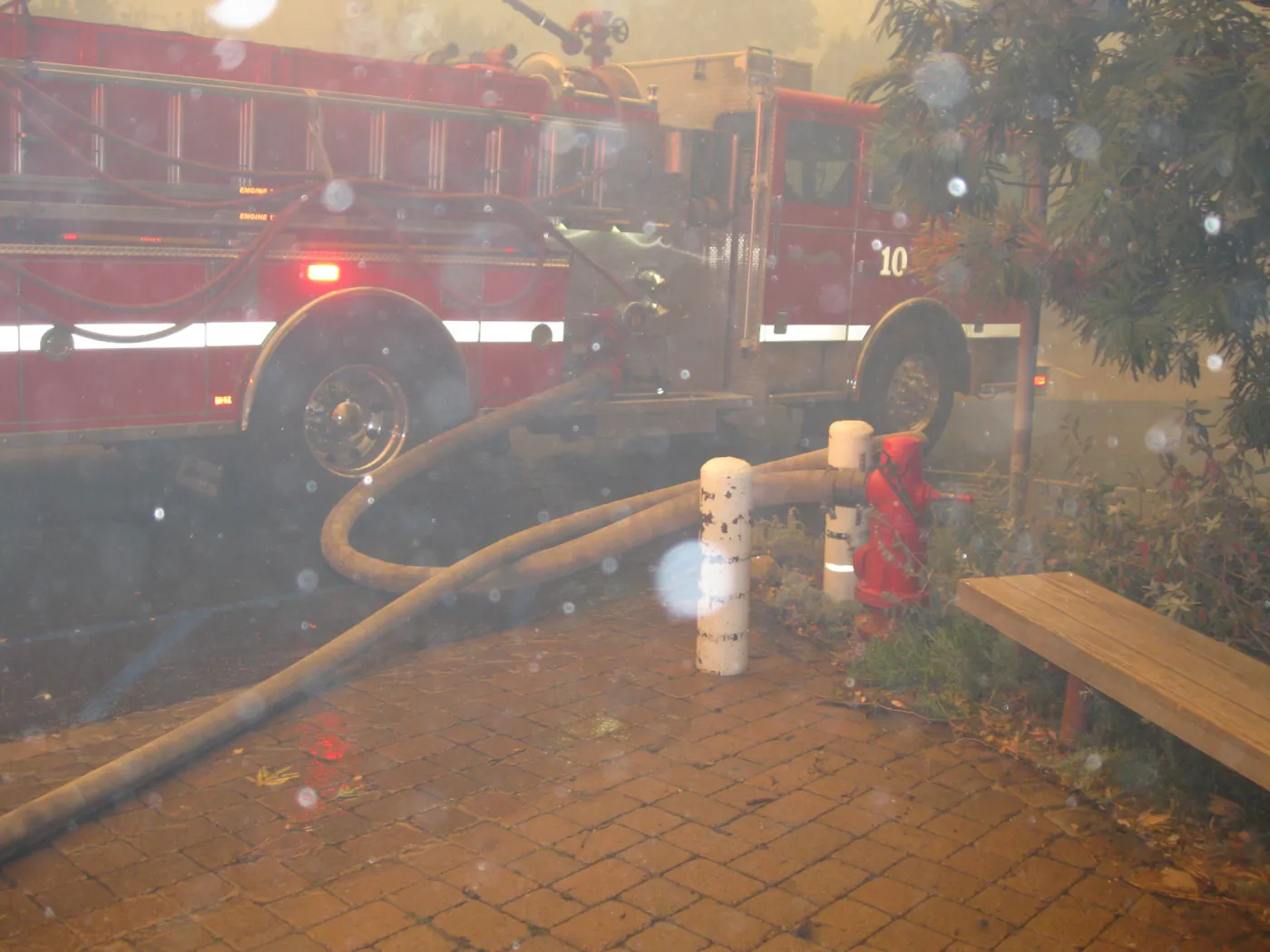 Fire truck with hose attached to the fire hydrant at the main entrance, during the Jesusita Fire