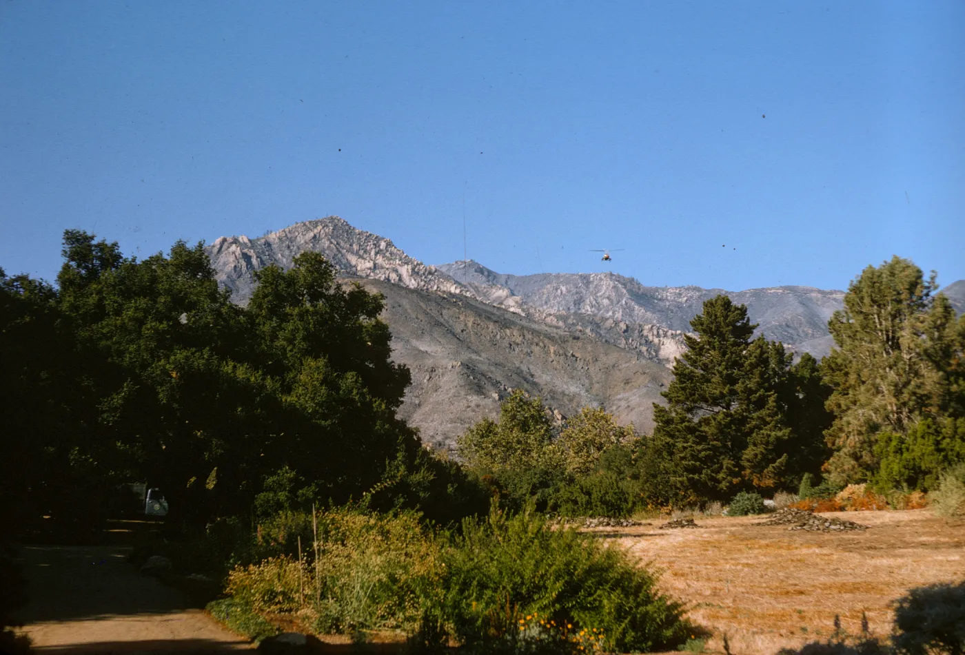 View of helicopter seeding Santa Ynez Mtns after Coyote Fire