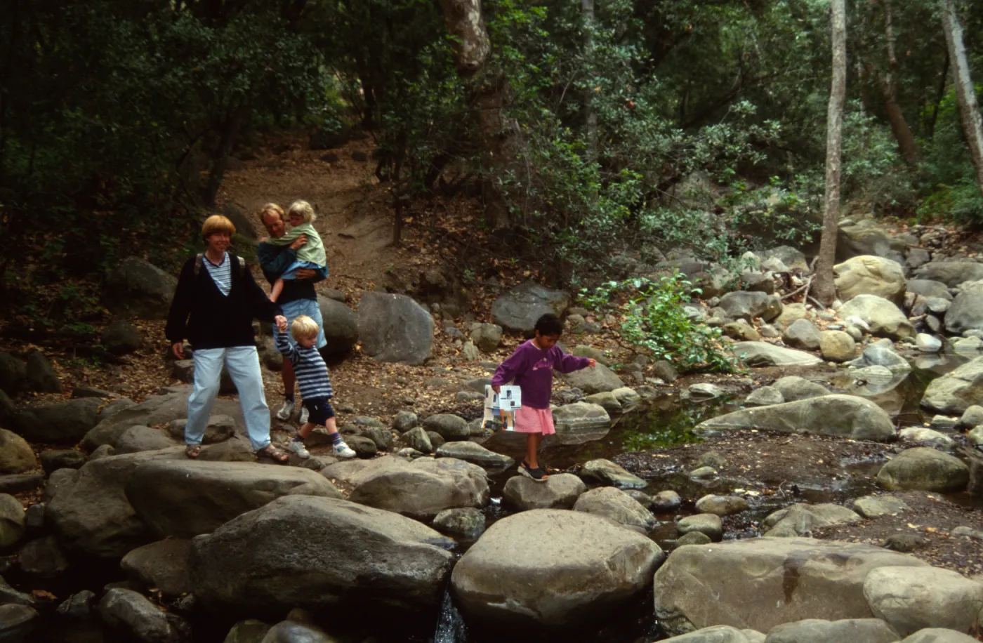 family crossing Mission Creek on boulders at creek crossing