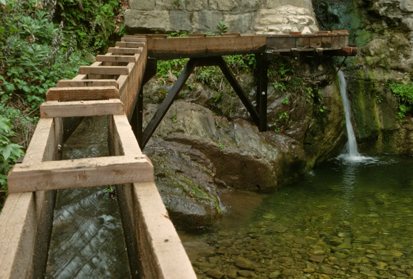 wooden aqueduct with flowing water and waterfall under Mission Dam