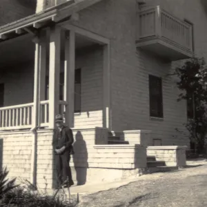 T. M. George by their porch with hat on