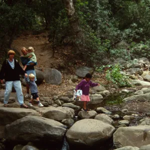 family crossing Mission Creek on boulders at creek crossing