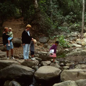 family crossing Mission Creek on boulders at creek crossing