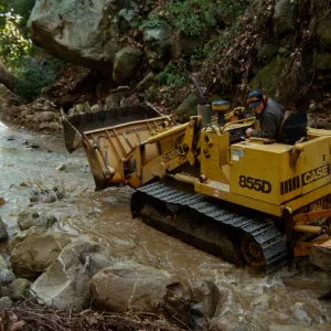 using a tractor to clear Mission Creek above Mission Dam